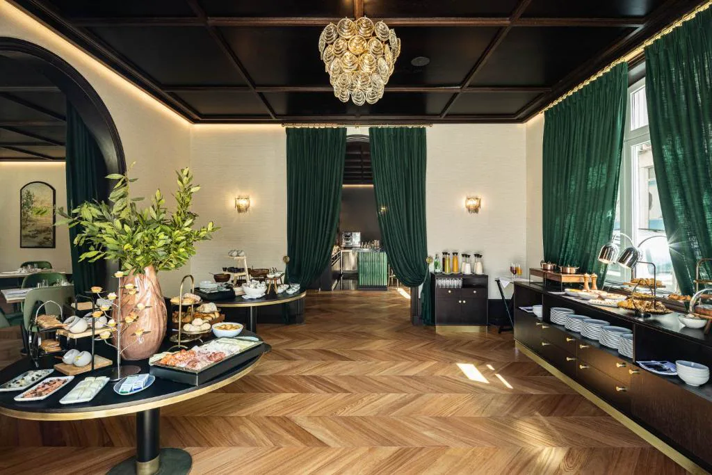 Sala de desayunos con cortinas verde esmeralda y lámpara de cristal, Palacete Valdemouro