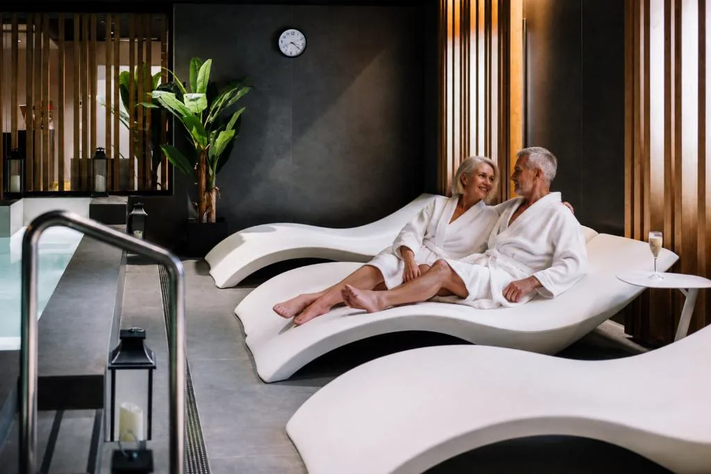 Sala de relax con tumbonas blancas y albornoces