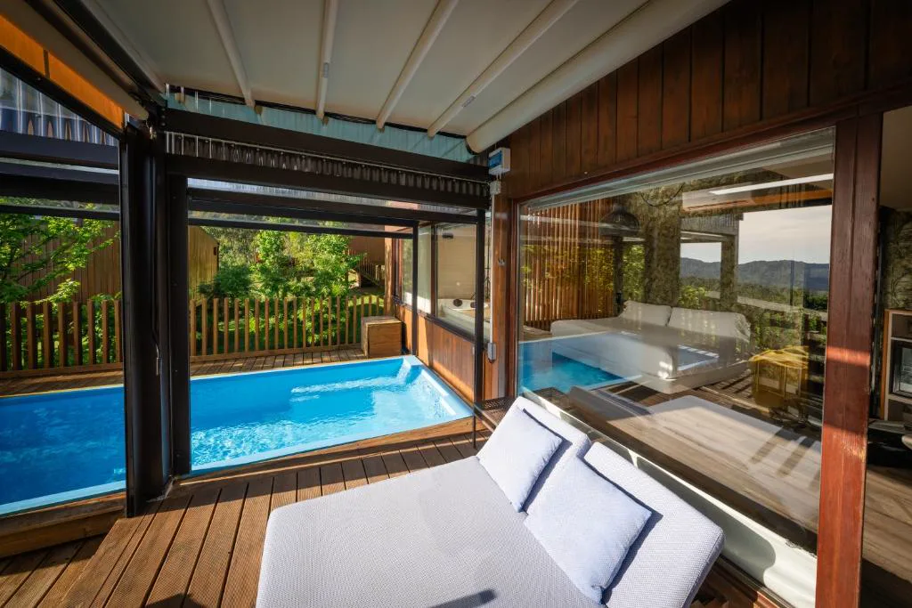 Piscina privada con paredes de cristal y tumbona junto a las montañas, Nidos de Carnota