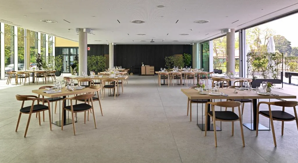 Comedor del gastrobar Qomo con mesas de madera y vistas al jardín, Noa Boutique Hotel