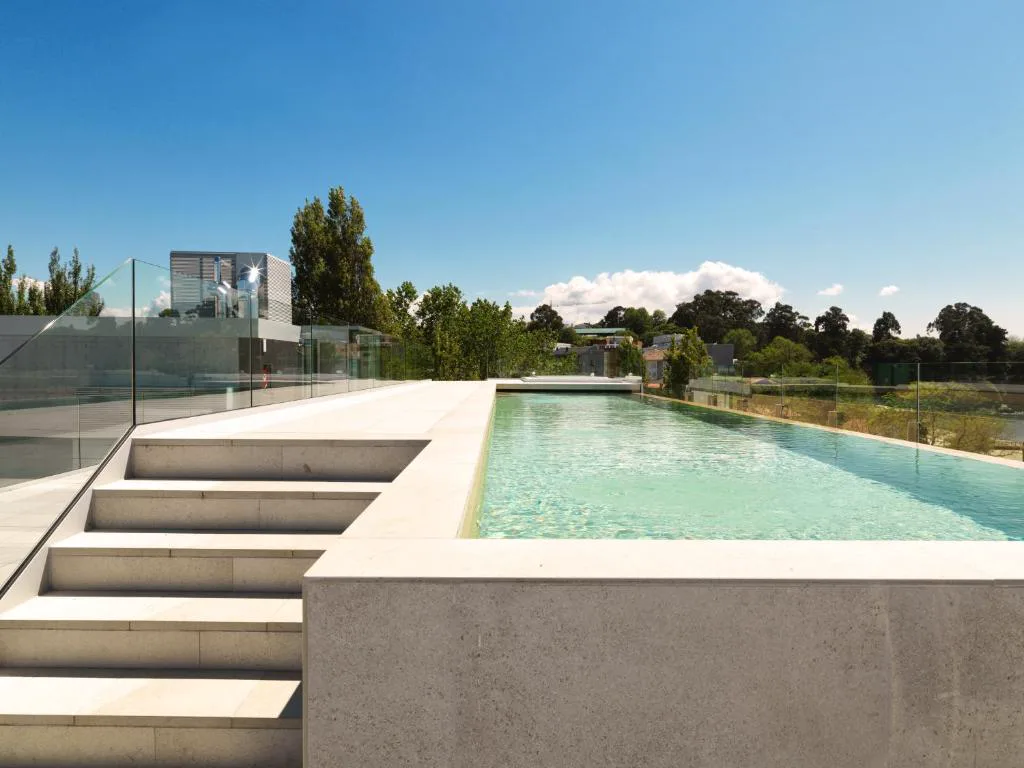 Piscina infinita en la azotea con vistas al mar y a los edificios de Santa Cruz de Oleiros, Noa Boutique Hotel