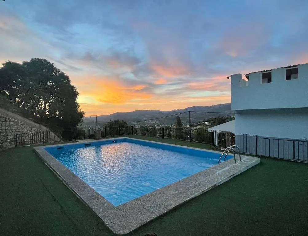 Piscina rectangular al atardecer con montañas al fondo
