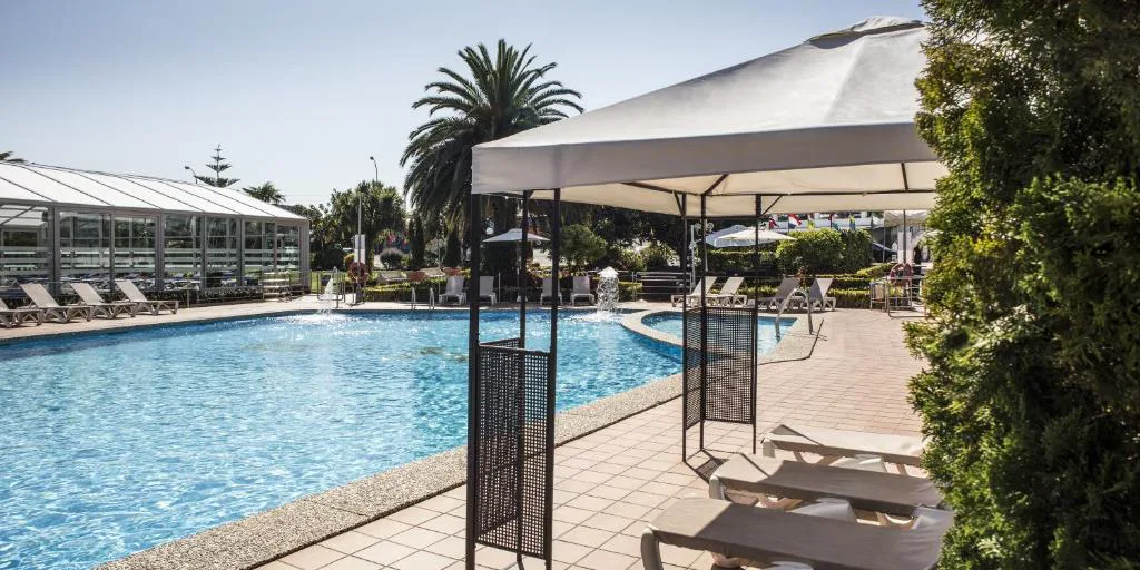 Piscina exterior con fuente y palmeras junto al pabellón de cristal, Nuevo Astur Spa