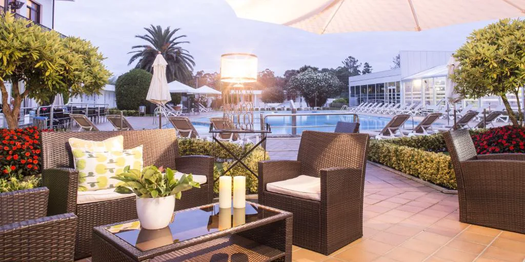 Terraza con sofás de mimbre junto a la piscina al atardecer, Nuevo Astur Spa