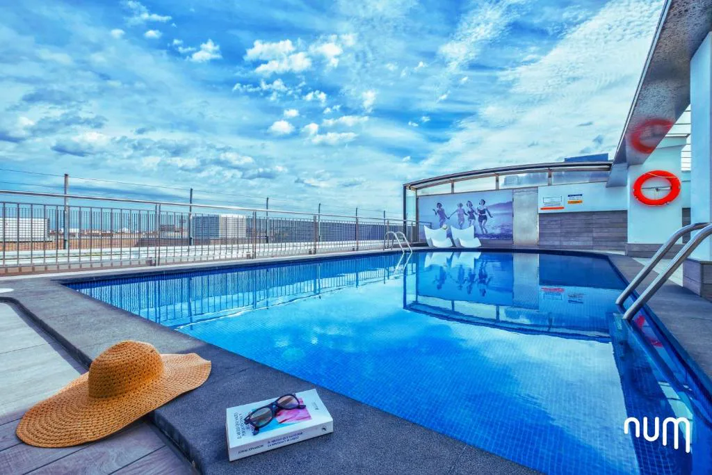 Piscina azul en la azotea con toalla y sombrero sobre una tumbona