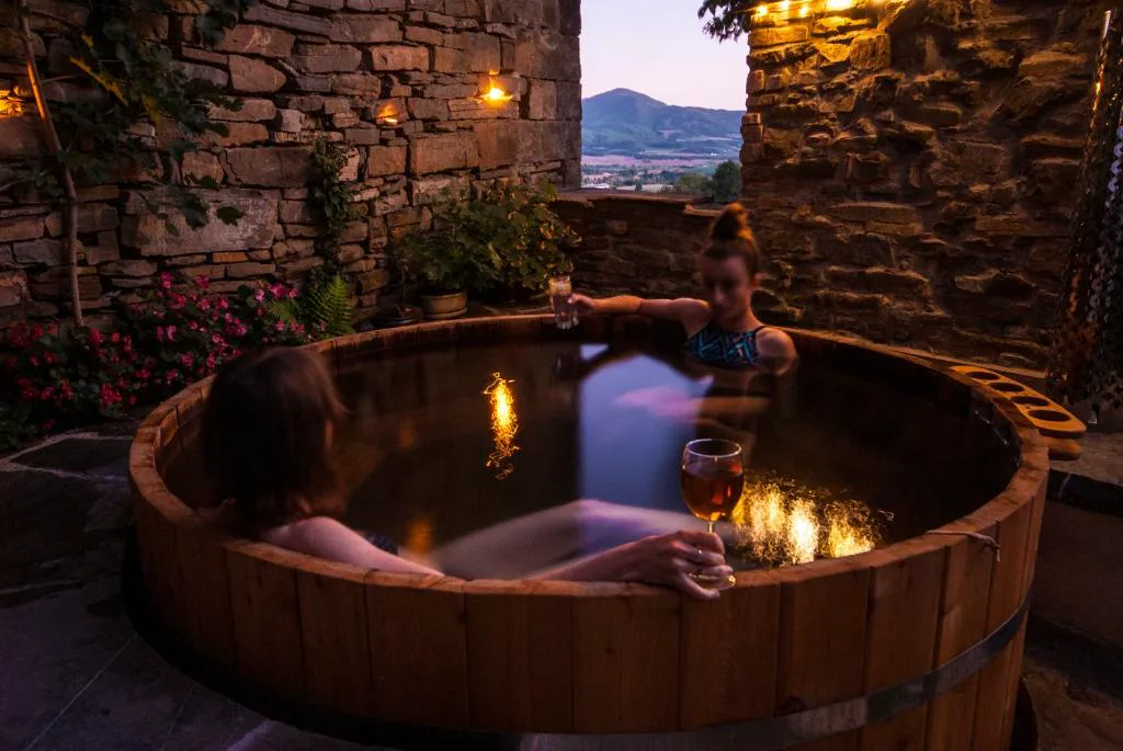 Jacuzzi de madera con velas en un patio de piedra