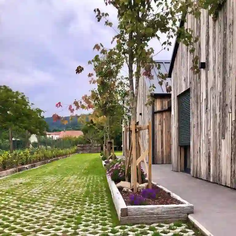 Jardín con arces y camino de piedra junto a la fachada de madera, Casitas O Loureiro