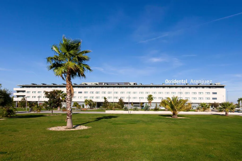 Hotel de líneas horizontales con césped y una palmera