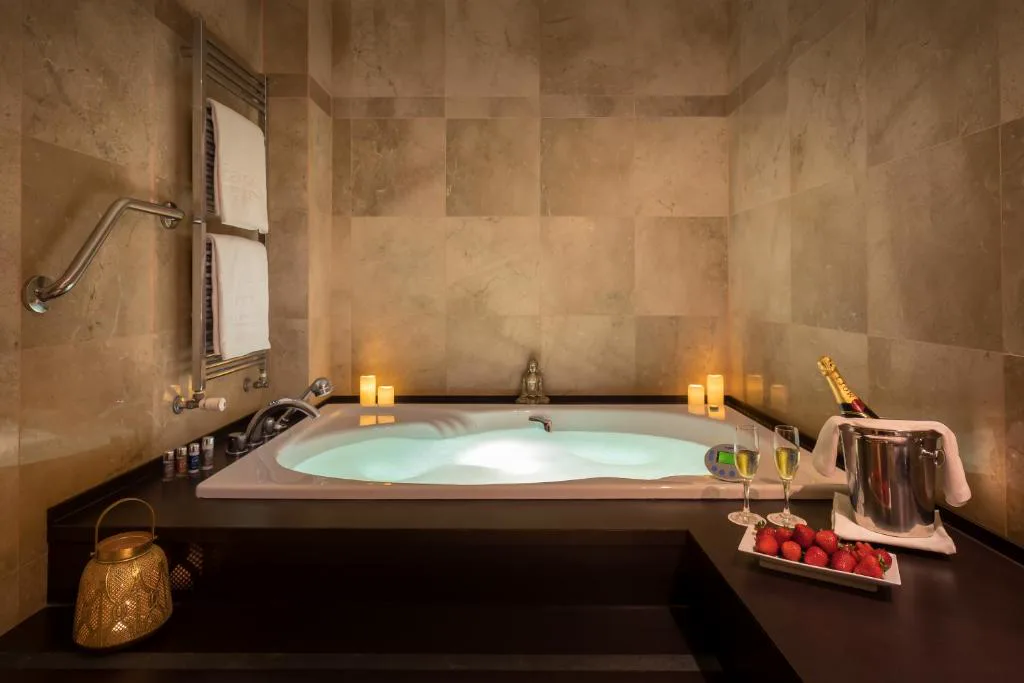 Bañera de hidromasaje con velas y toallas en una sala de piedra