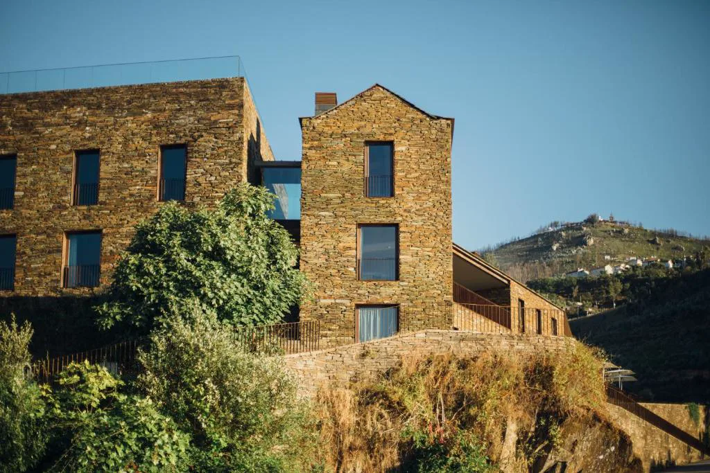 Edificio de piedra tradicional junto a las terrazas de cristal del hotel, Octant Douro