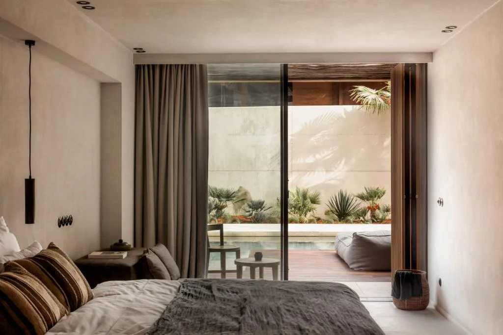 Dormitorio con vistas a un patio con piscina y plantas, OKU Ibiza