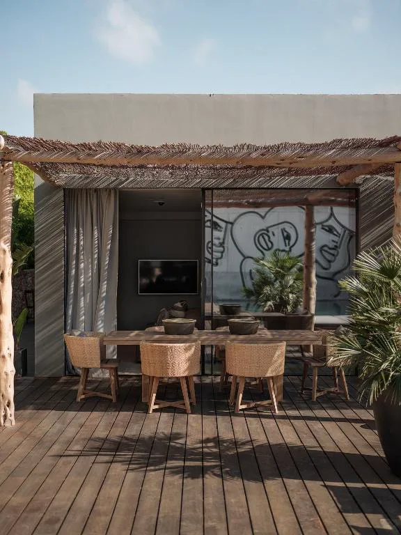 Pérgola exterior con mesa y mural artístico en la pared, OKU Ibiza