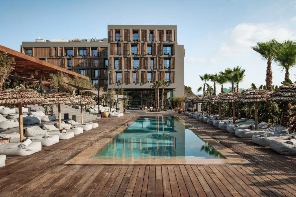 Piscina con camas balinesas y palmeras de OKU Ibiza, hotel de diseño en San Antonio
