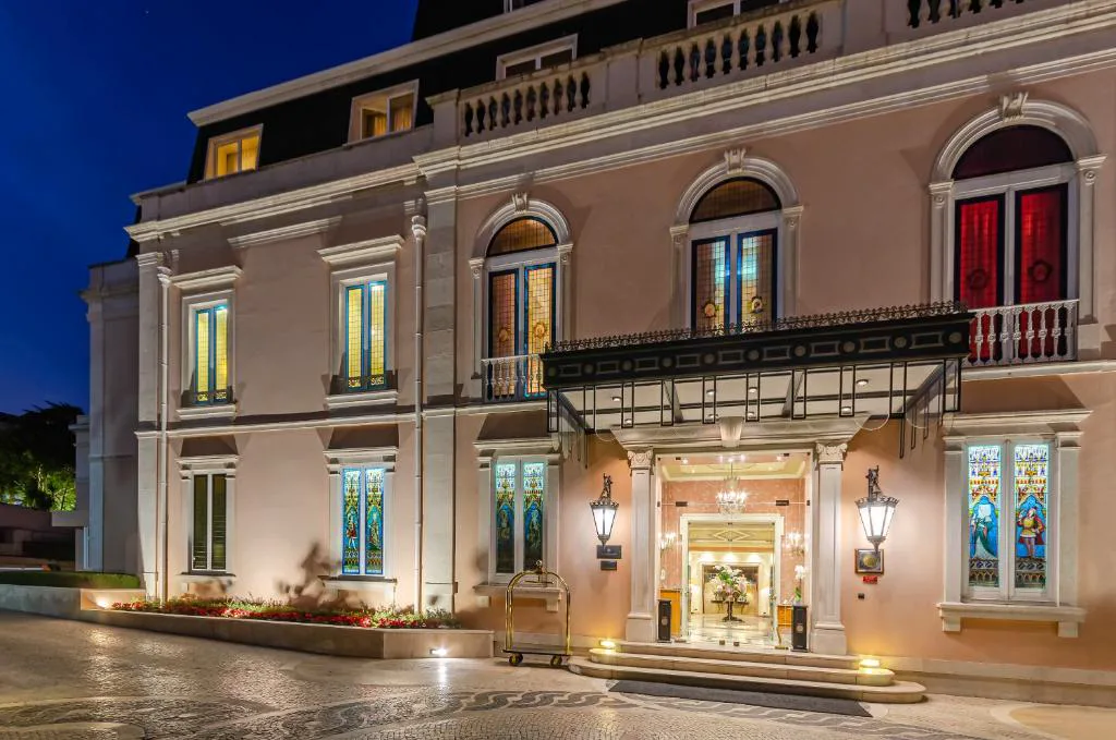 Fachada nocturna del Olissippo Lapa Palace con vidrieras y entrada iluminada