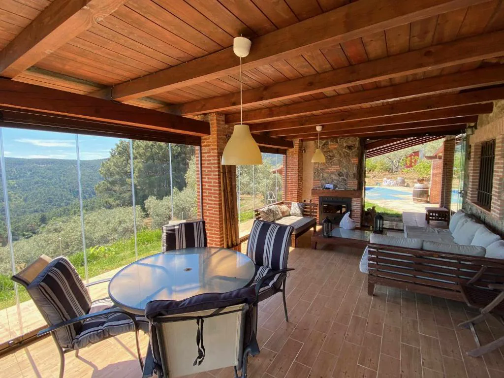 Comedor acristalado bajo vigas de madera con vistas a la montaña
