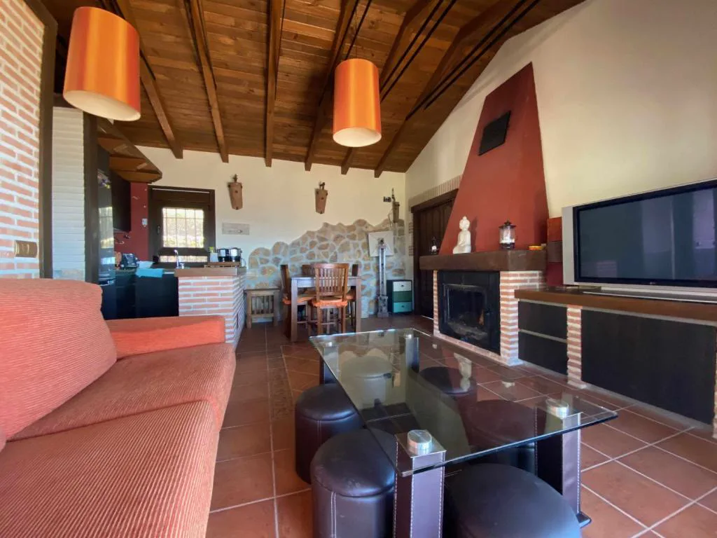 Salón con sofá naranja, chimenea y televisión bajo techo de madera