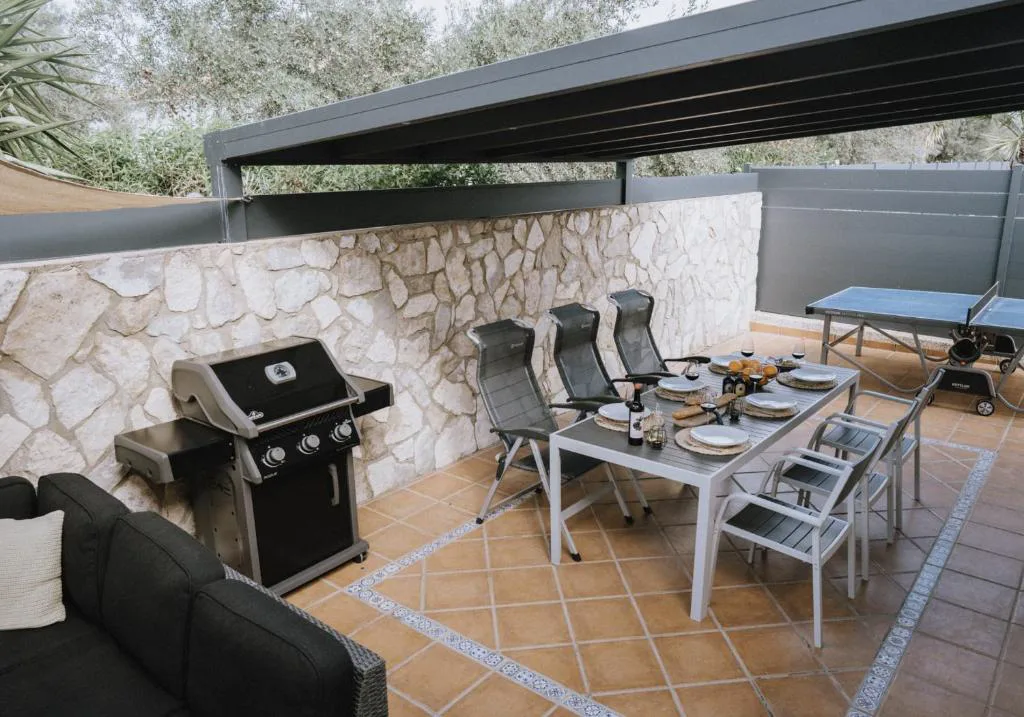Barbacoa y mesa exterior bajo pérgola