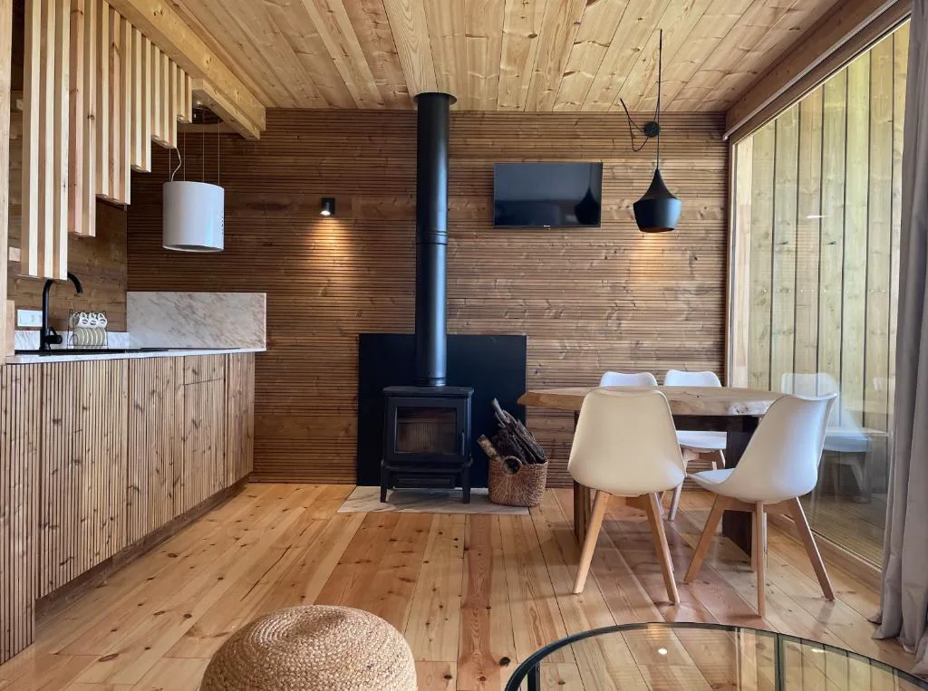 Estufa de leña negra junto a la mesa de comedor de madera maciza, Olladas de Barbeitos