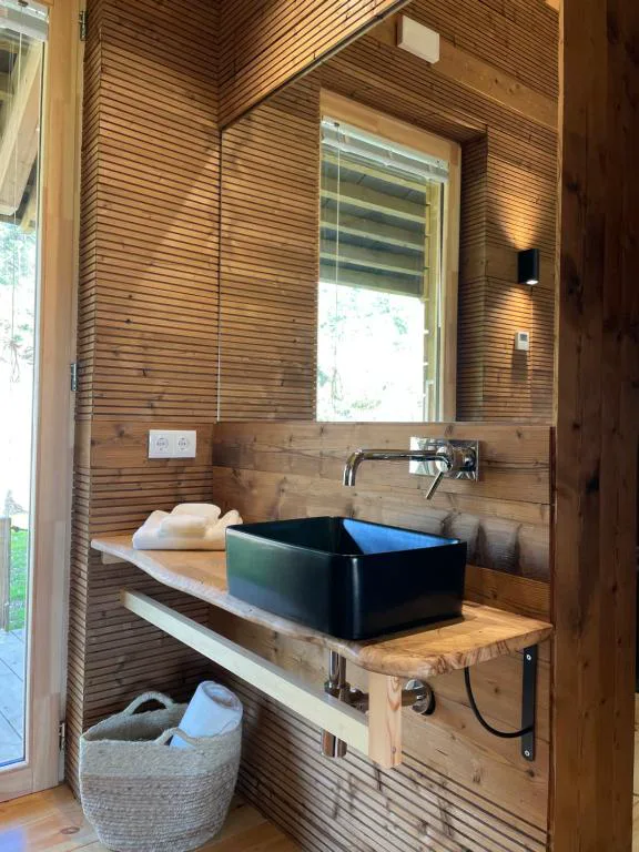 Baño de diseño con lavabo de cerámica negra sobre encimera de madera, Olladas de Barbeitos