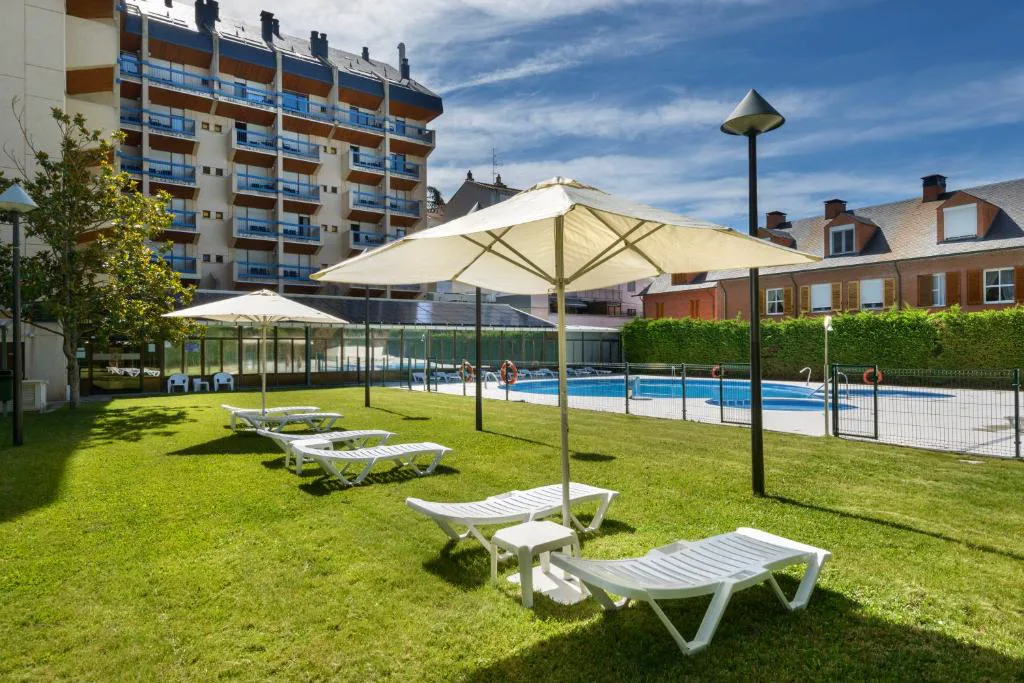 Jardín con tumbonas y sombrillas junto a la piscina
