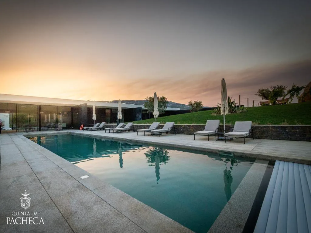 Piscina exterior al atardecer junto al edificio de spa de Quinta da Pacheca