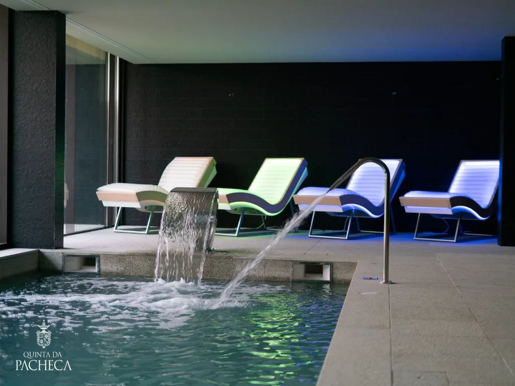 Piscina cubierta del spa con cascadas de hidromasaje y tumbonas iluminadas, Quinta da Pacheca