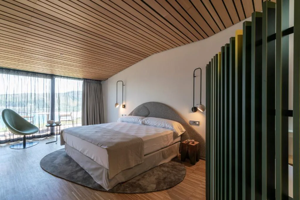Dormitorio de diseño con techos de madera y vistas al valle, Parador Costa da Morte