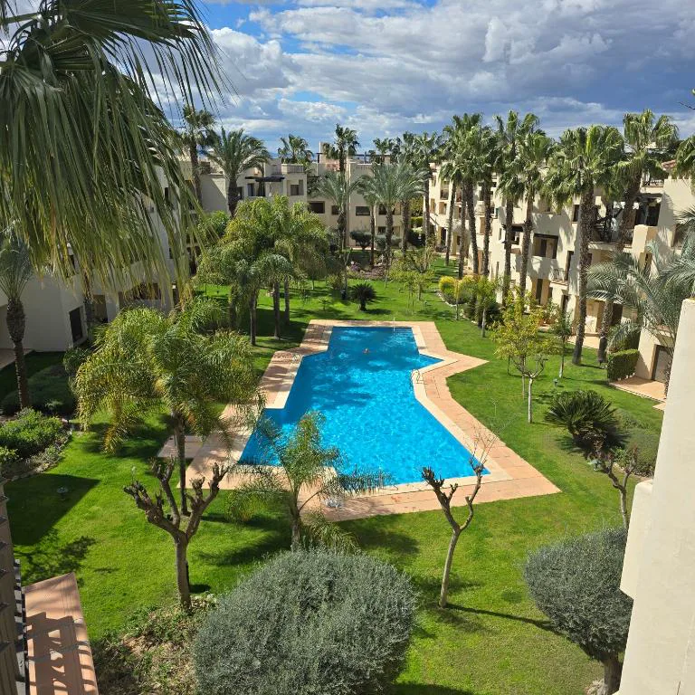 Piscina comunitaria con jardín y palmeras del resort