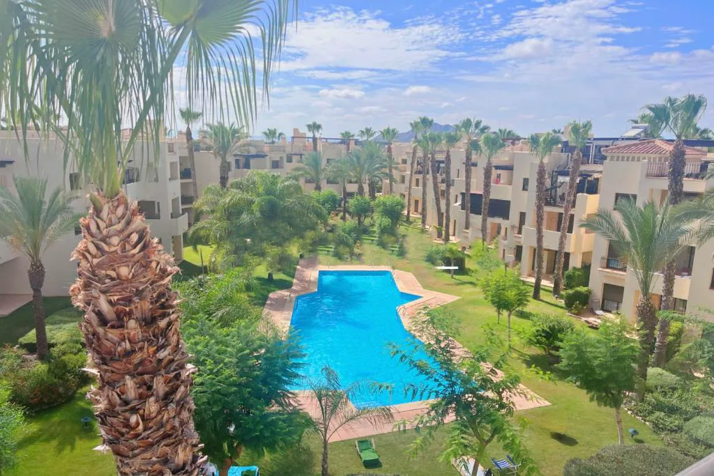 Piscina comunitaria entre bloques de casas y palmeras