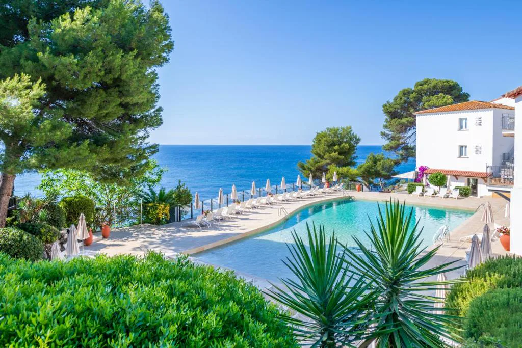 Piscina con vistas al Mediterráneo y el hotel blanco