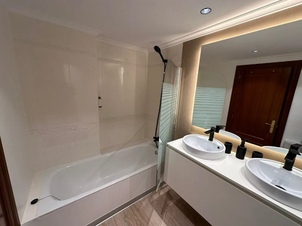 Baño con ducha y encimera blanca
