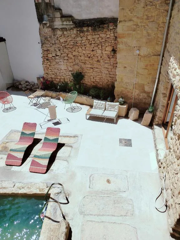 Patio de piedra con piscina y tumbonas