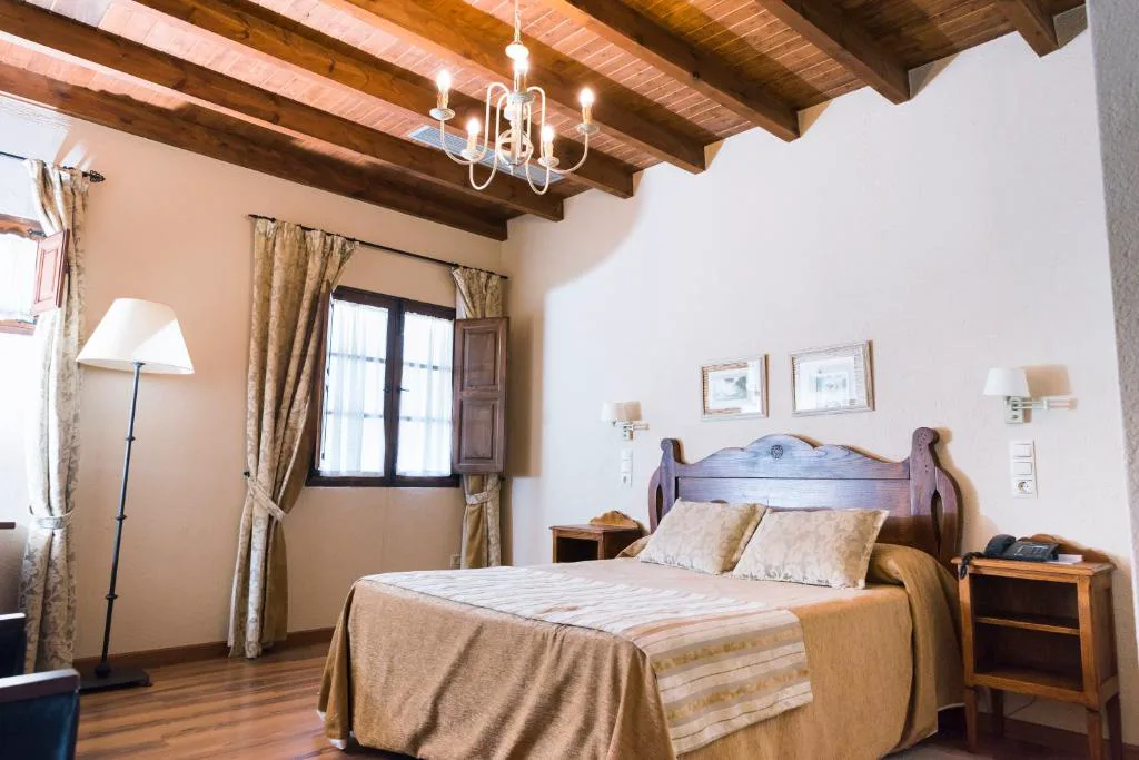 Dormitorio con vigas de madera vista y cabecero de anticuario, Pazo do Castro