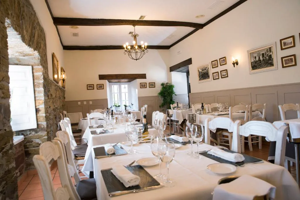 Comedor con lámpara de araña y mesas vestidas de blanco, Pazo do Castro