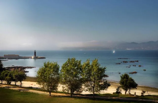 Vistas a la ría de Vigo con un faro y un velero desde los jardines, Pazo Los Escudos