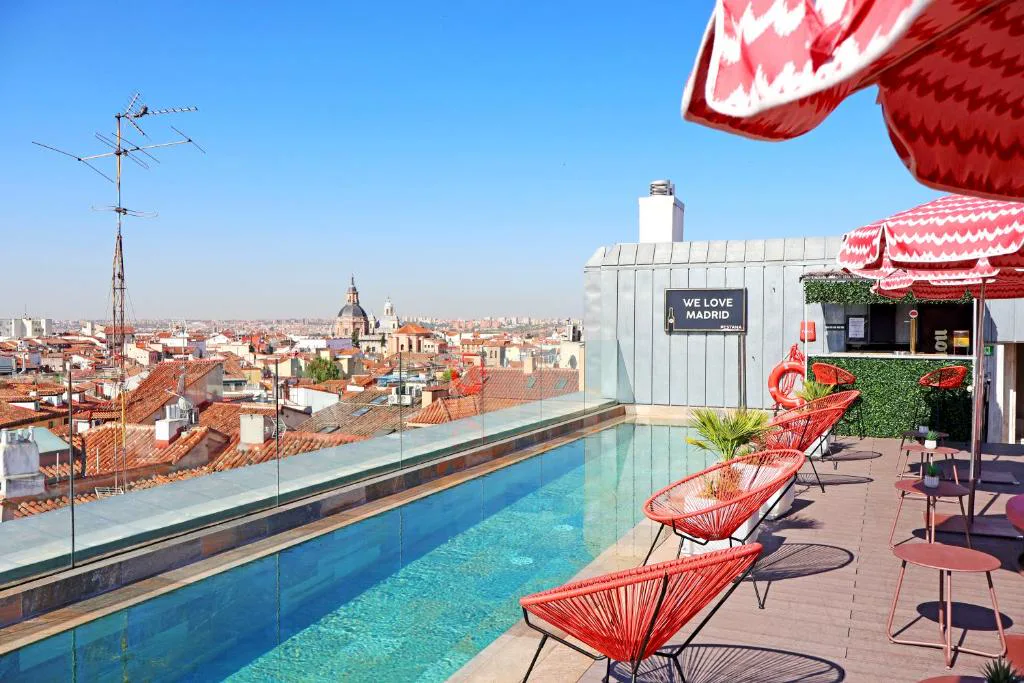 Piscina de azotea con tumbonas rojas y vistas a los tejados de Madrid