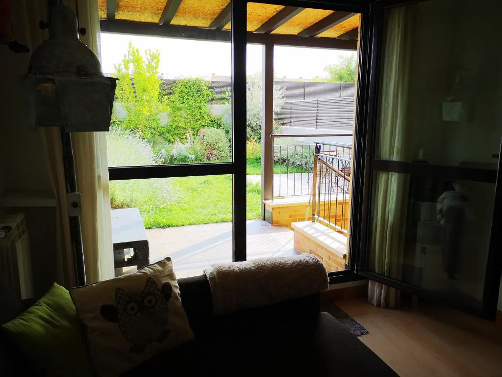 Salón con sofá gris y ventanal al jardín