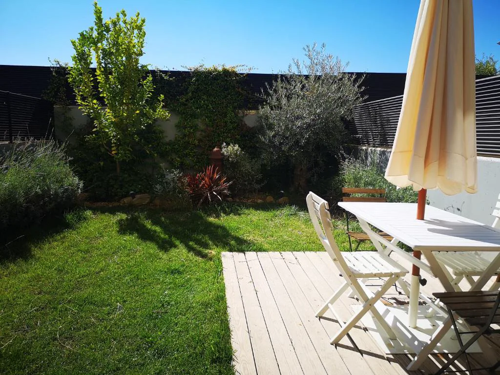 Terraza con césped y pérgola blanca
