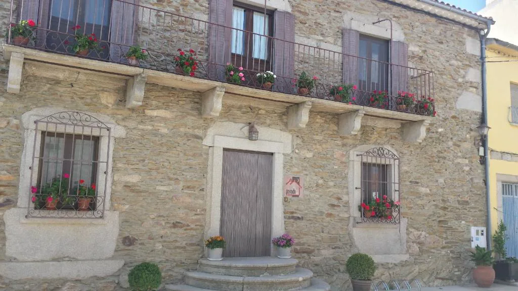 Fachada de piedra con balcón de hierro y ventanas de madera