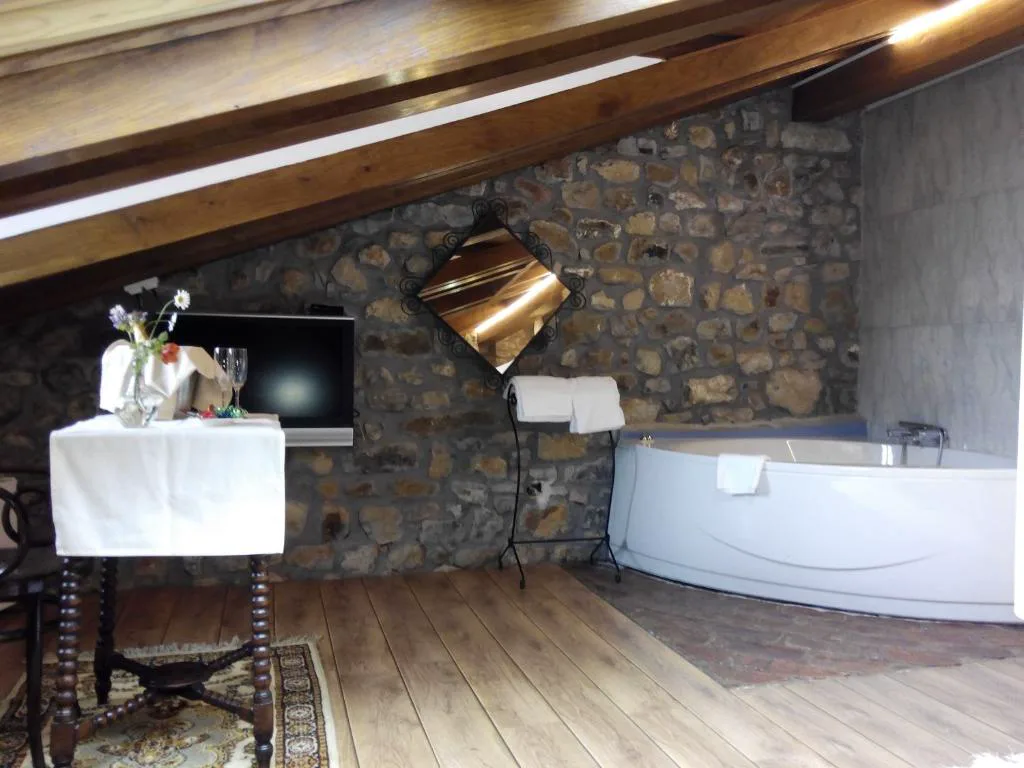 Habitación con bañera de esquina y televisión sobre la pared