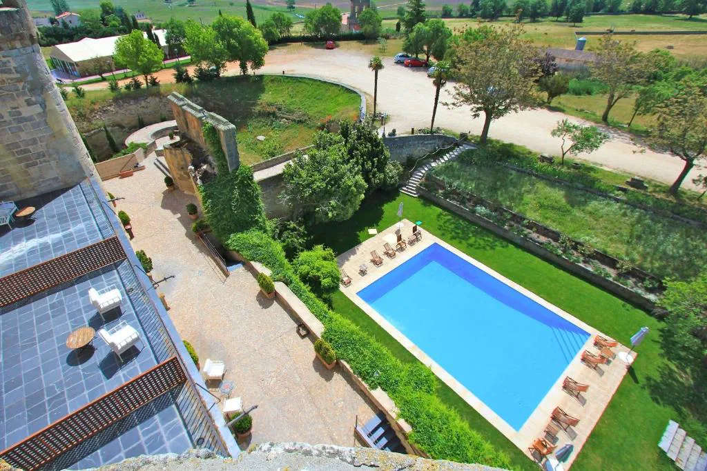 Piscina azul rodeada de jardín vista desde lo alto del castillo