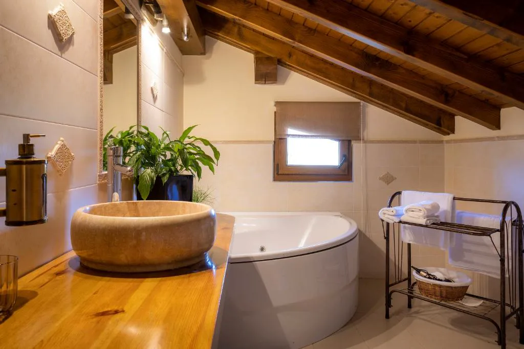 Baño abuhardillado con bañera de esquina y lavabo de piedra
