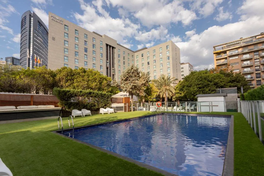 Piscina exterior con tumbonas junto a los edificios del hotel