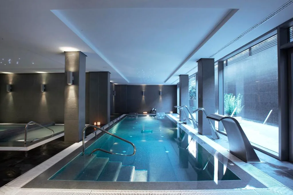 Piscina interior del spa con chorros de agua y ventanal