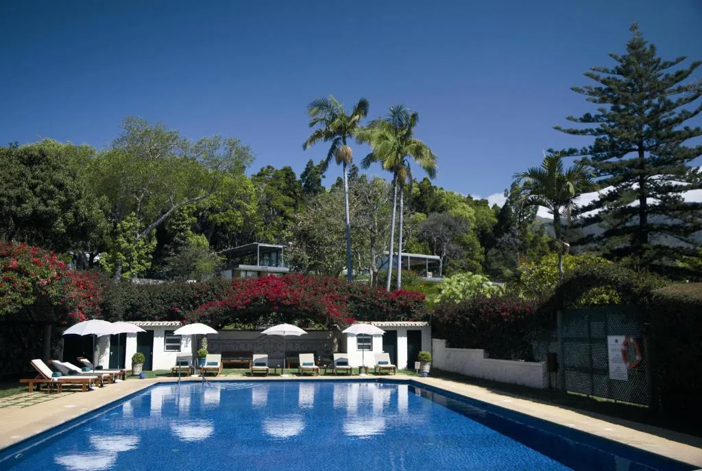 Piscina exterior de Quinta da Casa Branca rodeada de palmeras y buganvillas