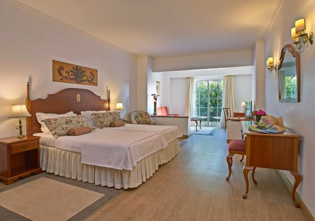 Habitación clásica con cabecero de madera y acceso a un balcón ajardinado, Quintinha Sao Joao