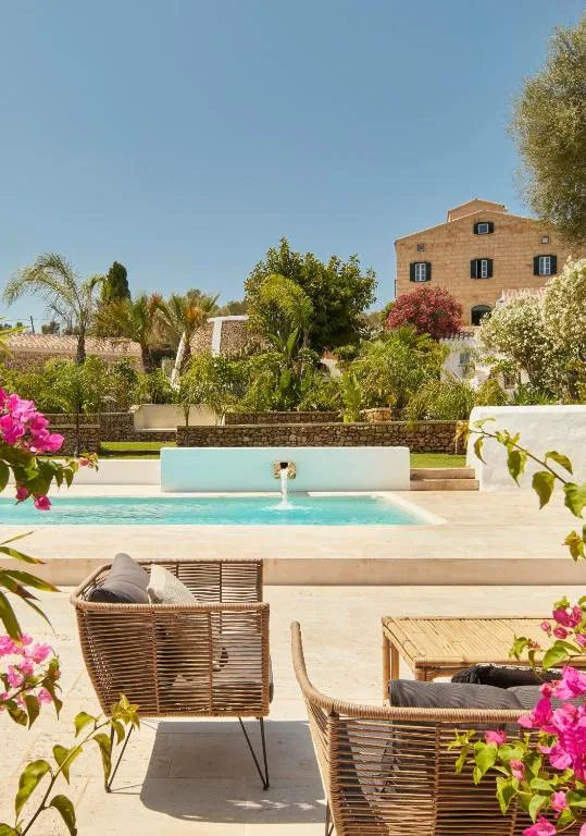 Piscina con fuente de piedra y jardín de buganvillas en Agroturismo Rafal Rubí, Alaior, Menorca