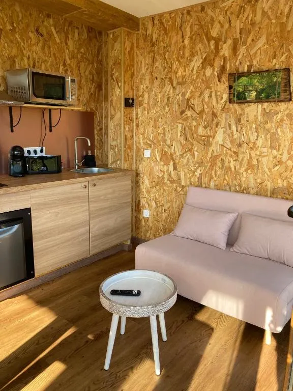 Cocina y salón en madera clara con sofá rosa, O Refuxio dos Cebreiros en Mazaricos