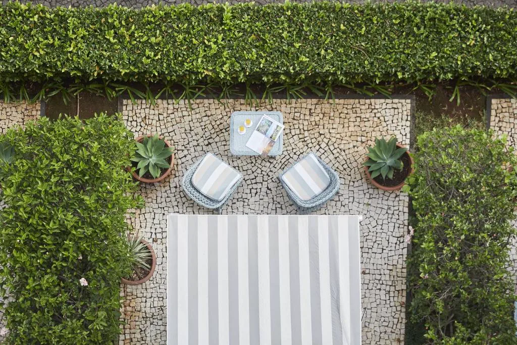 Terraza con mesa para el desayuno vista desde arriba, entre setos de jardín, Reid's Palace