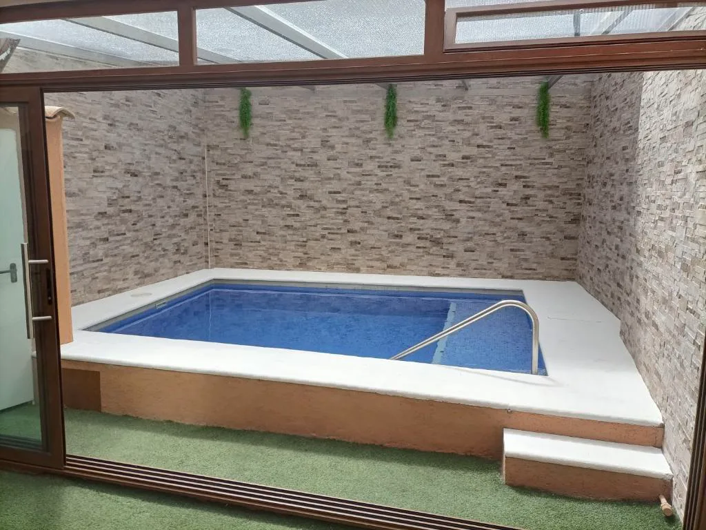 Piscina pequeña en un patio de piedra con ventanal